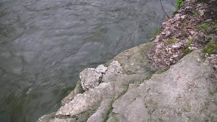 A rocky edge with a small drop to a flowing spring river.  Speed river, Guelph, Ontario