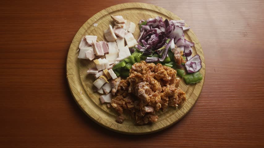 High Angle Zoom In on Chopped Ingredients on Wooden Cutting Board, Top Down View of Diced Bacon Sausage Red Onion and Green Pepper