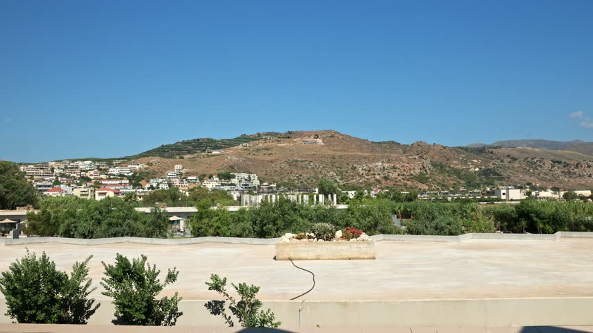 Beautiful view of hillside town with houses, rocky mountains and vegetation on sunny day. Crete. Greece.