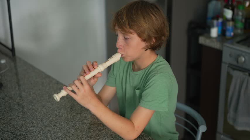 A little boy learns to play the flute at home, practicing with focus and enthusiasm in a cozy, warm setting. A charming scene of early musical exploration, creativity, and childhood growth.