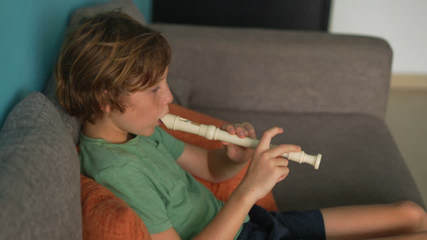 A little boy learns to play the flute at home, practicing with focus and enthusiasm in a cozy, warm setting. A charming scene of early musical exploration, creativity, and childhood growth.