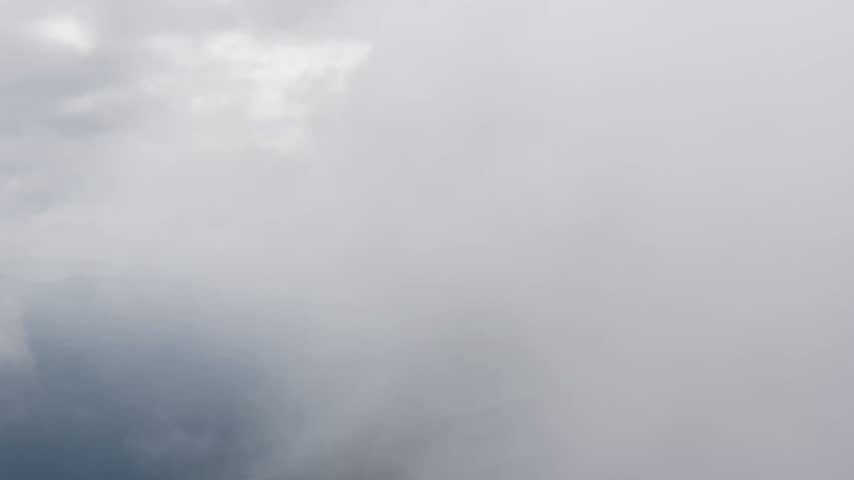Dramatic dense cloud formation rising over a mountainous hilly landscape aerial drone