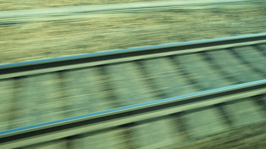 View of railroad tracks and motion blur ground from moving train