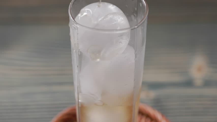 Peach Extract Juice Flowing Through Ice Cubes In Glass Close Up Slow Motion.
Close-up slow motion shot of fresh peach extract juice flowing through ice cubes in a glass. The golden peach beverage gradually moves between the ice cubes, creating an attractive view of liquid movement, bubbles, and chilled fruit drink. Ideal for summer beverage, food, commercial, advertising, lifestyle, and refreshing drink projects.