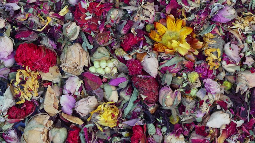 Colorful dried flower petals and buds forming a rotating herbal tea blend background with roses and marigold
