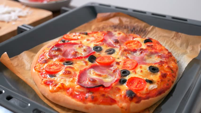 Beautiful kitchen video with homemade round pizza with 
vegetables, meat, olive, tomato, cheese, 
mayonnaise. Appetizing tasty dish.