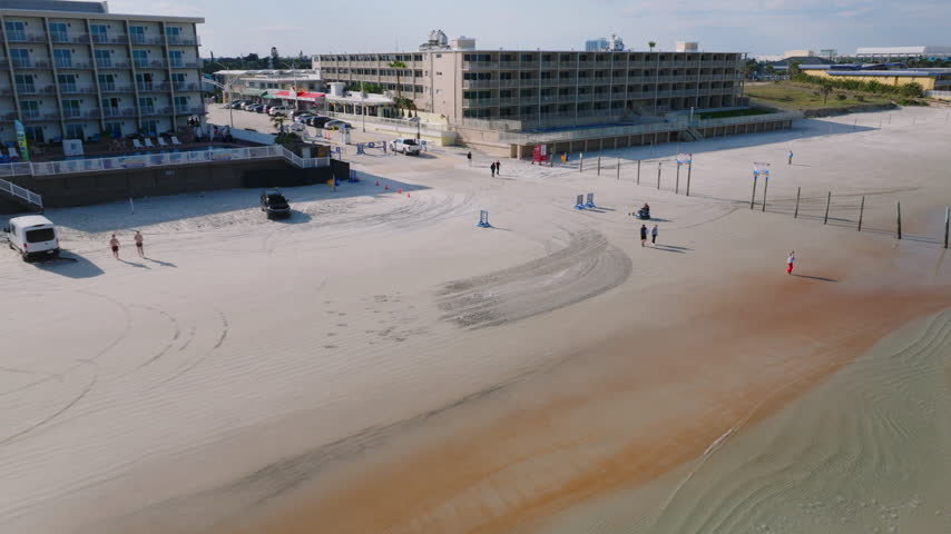 Aerial drone view of beachfront hotels along Daytona Beach, Florida, with Atlantic Ocean waves, sandy shoreline, and coastal cityscape, filmed in ProRes 422HQ