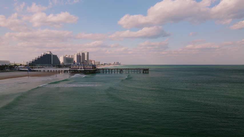 Aerial drone view of beachfront hotels along Daytona Beach, Florida, with Atlantic Ocean waves, sandy shoreline, and coastal cityscape, filmed in ProRes 422HQ