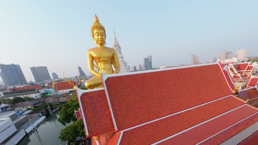 Cinematic FPV drone fly around giant golden Buddha at Wat Paknam temple in Bangkok, Thailand. Aerial movement over city skyline and Buddhist landmark.