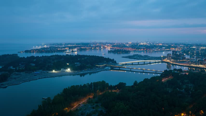 Aerial view of Mustikkamaa and Korkeasaari islands with illuminated bridges and city lights at dusk in Helsinki, Uusimaa, Finland. Hyperlapse.