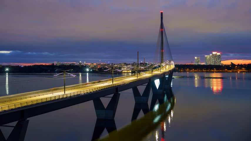 Aerial view of Kruunuvuorensilta bridge hyperlapse with city lights reflecting on the water at dusk in Helsinki, Uusimaa, Finland.