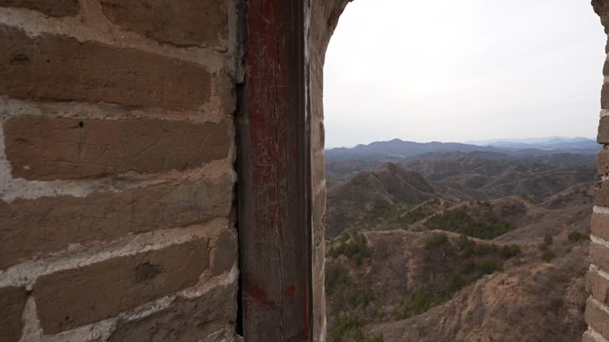 Landscape view through the window in a watch tower of the UNESCO Great Wall of China during daytime.