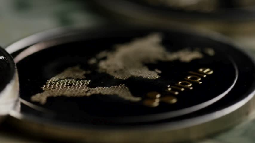 Macro close up shot of physical golden ripple cryptocurrency coins resting on real united states twenty and one hundred dollar paper banknotes