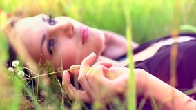 Beautiful Girl Lying on the Meadow and Dreaming. Enjoy Nature. Close up Slow Motion Footage
