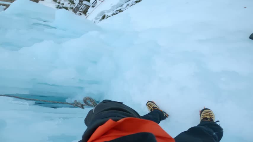 Point of view of an ice climber with gloved hands ascending a frozen ice wall, showcasing extreme outdoor adventure, climbing technique, winter sports, and icy mountain scenery.
