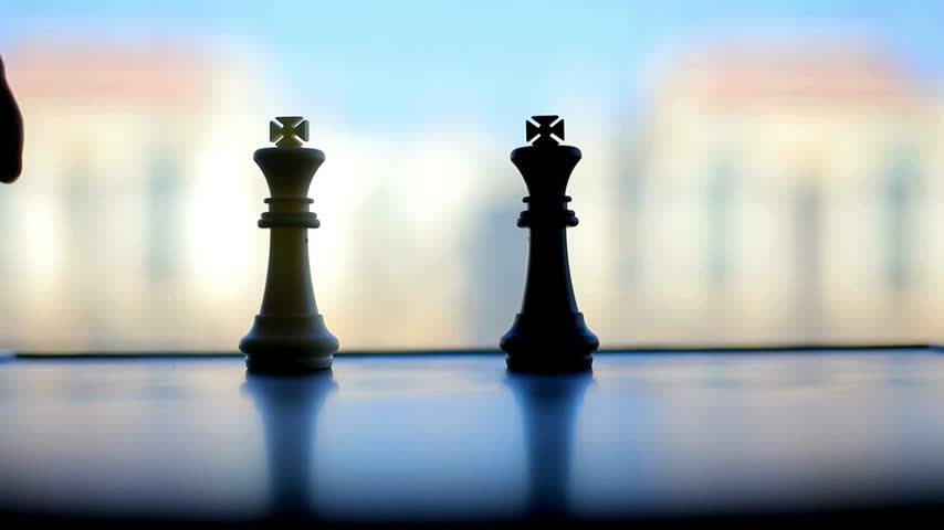 Close-up of a hand moving a King piece on a chessboard, executing a strategic move in a classic intellectual board game against the opponent