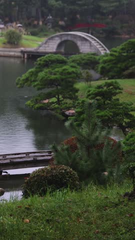 Shukkeien traditional Japanese garden in Naka-ku,  Shukkei-en garden, Hiroshima city, Chugoku region, Japan, with pond and trees, thatched roof teahouse pavilion reflection in a rainy autumn day