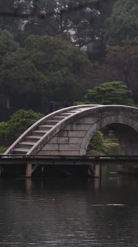 Shukkeien traditional Japanese garden in Naka-ku,  Shukkei-en garden, Hiroshima city, Chugoku region, Japan, with pond and trees, thatched roof teahouse pavilion reflection in a rainy autumn day