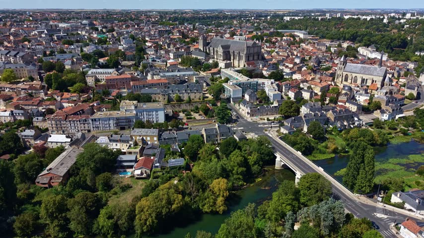 Poitiers rises above the Clain River with Saint-Pierre Cathedral and Notre-Dame-la-Grande visible among the historic center, while Pont Neuf crosses the river below in Vienne, France, drone slide