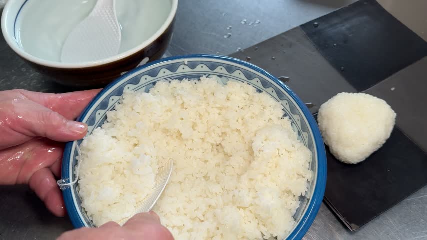 Chef hands shaping onigiri rice balls for yaki onigiri, Japanese food preparation in izakaya kitchen, Japan