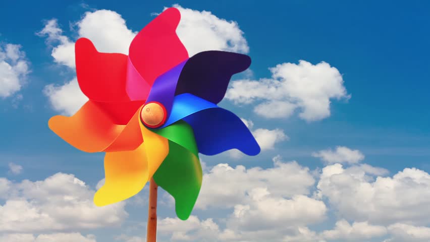 Colorful pinwheel toy against blue sky and white clouds
