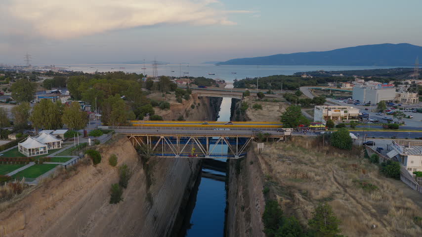 Drone tracking left above Corinth Canal at sunset with bridges in Greece, aerial