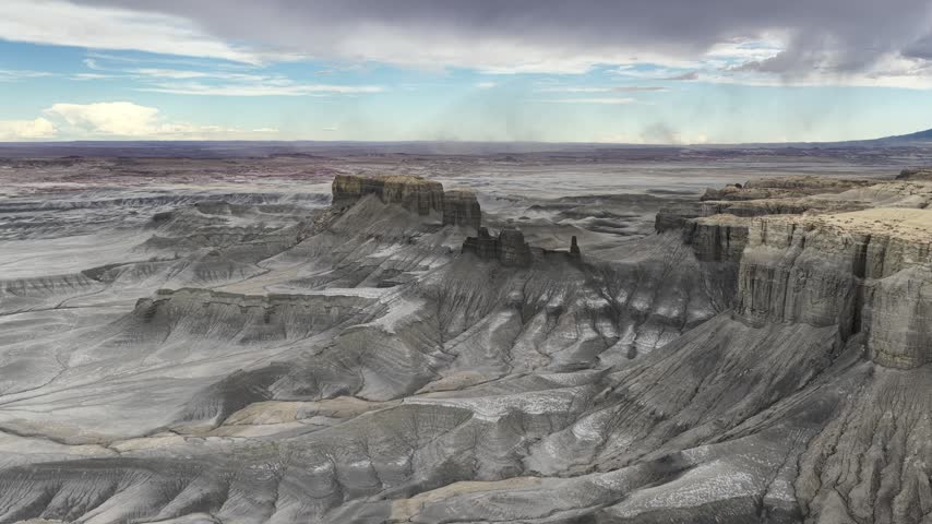 Aerial view of Moonscape Overlook featuring dramatic grey badlands and desert rock formations under a cloudy sky in Hanksville, Utah, United States.