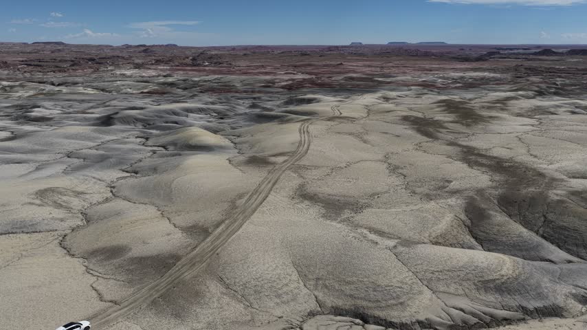 Aerial view of Moonscape Overlook featuring rugged desert terrain and tire tracks winding through the landscape in Hanksville, Utah, United States.