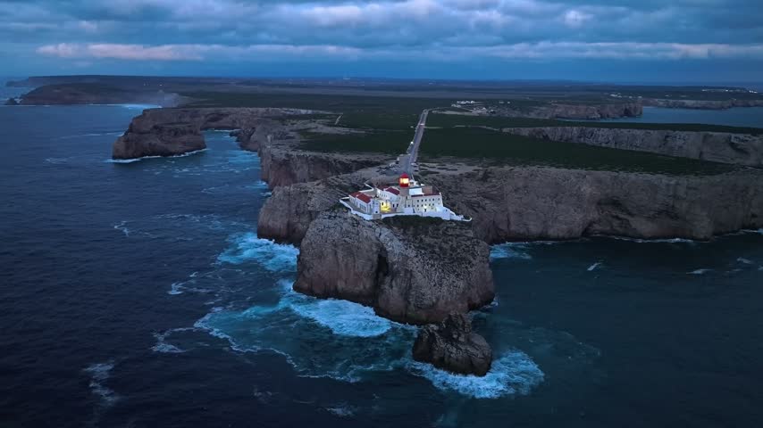 Drone view of the Lighthouse of Cabo de Sao Vicente in Sagres, Algarve, Portugal, at night with dramatic clouds and Atlantic ocean. Orbit parallax shot
