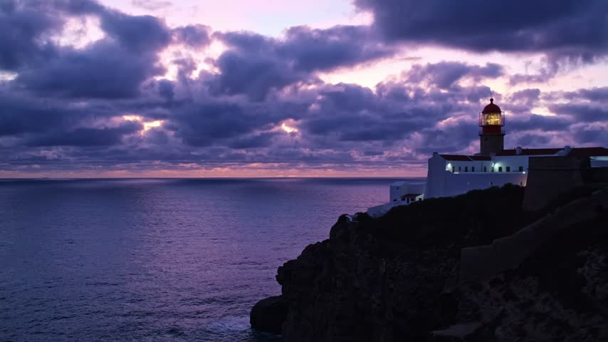 View of the Lighthouse of Cabo de Sao Vicente in Sagres, Algarve, Portugal, at dusk with purple clouds and Atlantic ocean