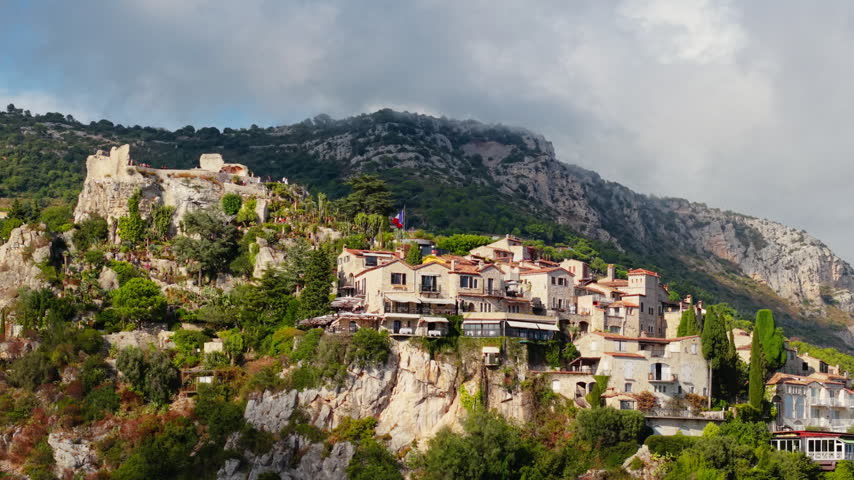 Hilltop stone village with medieval ruins and lush greenery overlooking the Riviera