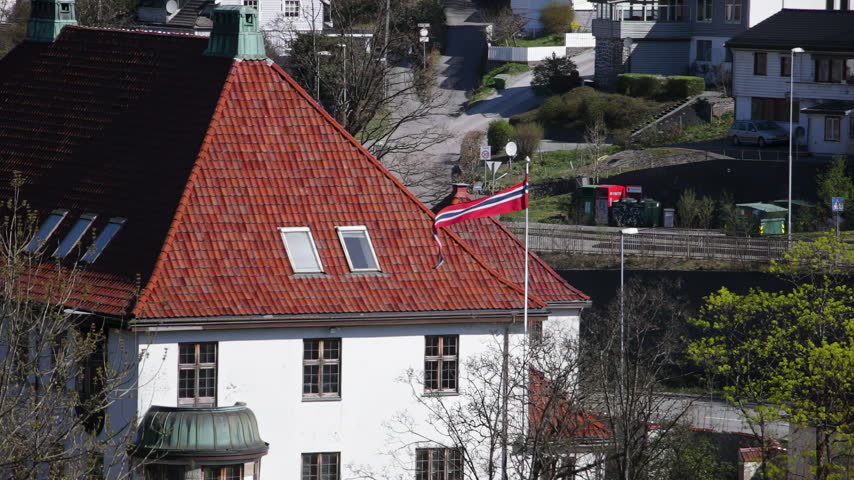 Norwegian flag waving on rooftop of historic building in Bergen residential area