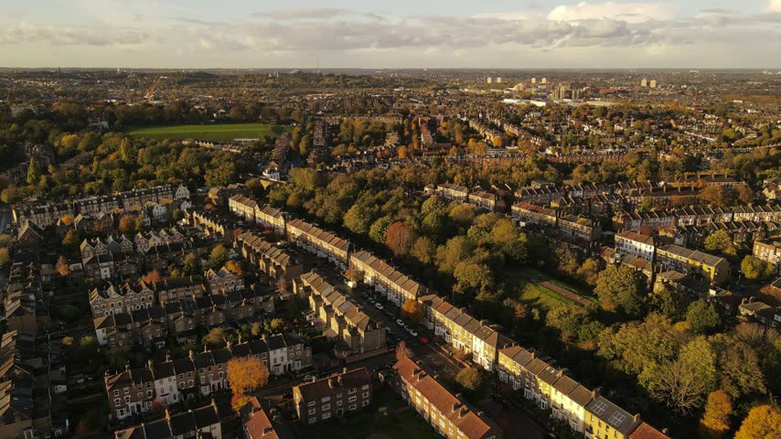 Aerial view of Finsbury Park and surrounding Victorian terraced houses with autumn foliage under golden hour light in London, England, United Kingdom.