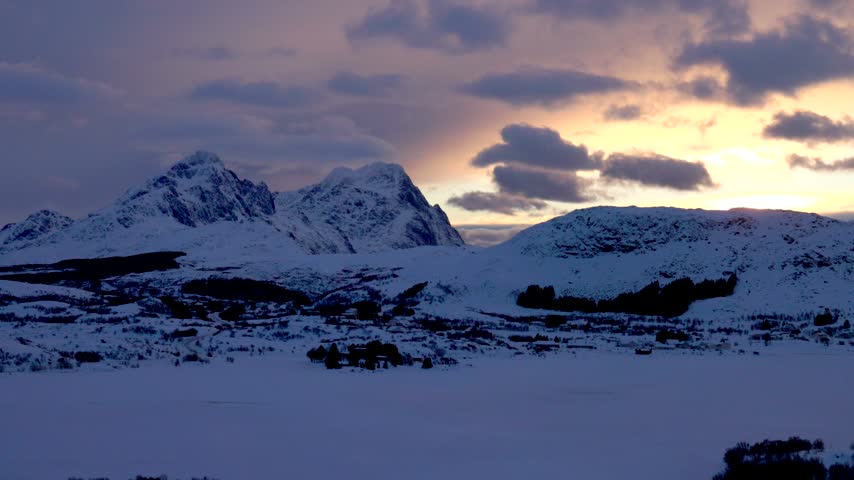 View of snow-covered Lofoten mountains under a soft sunset sky in Svolvaer, Nordland, Norway.