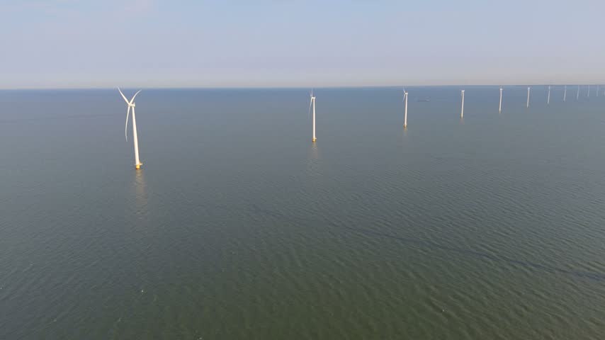 Majestic windmill turbines stand tall in the lush landscape of Ijsselmeer, Netherlands. Delight in the serene beauty and clean energy embodied in this coastal haven, perfect for travel enthusiasts.