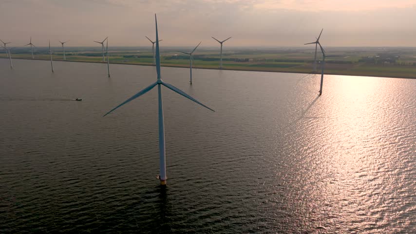 Witness the stunning landscape of Ijsselmeer in the Netherlands as majestic windmill turbines stand tall against the horizon, showcasing a blend of nature and technology at sunset.