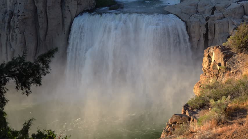 View of Shoshone Falls cascading over rocky cliffs with mist rising from the water in Twin Falls County, Idaho, United States.