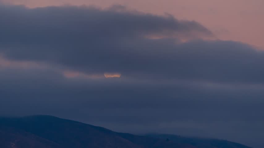 View of rolling mountains under a dramatic cloudy sky at dusk in Boise, Idaho, United States.