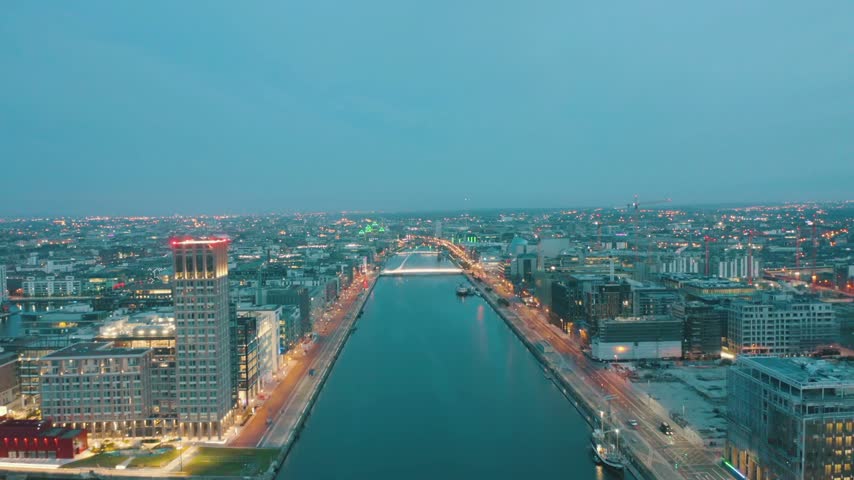 Aerial night flight over Dublin, Ireland, showcasing the illuminated cityscape, River Liffey, boats, bridges, waterfront lights, and dramatic urban views.