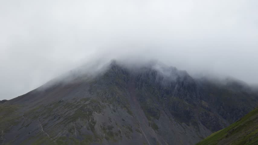 Great Gable in mist as low cloud drifts across rugged rocky summit and scree slopes, static landscape shot in Lake District National Park, Cumbria, England, UK.