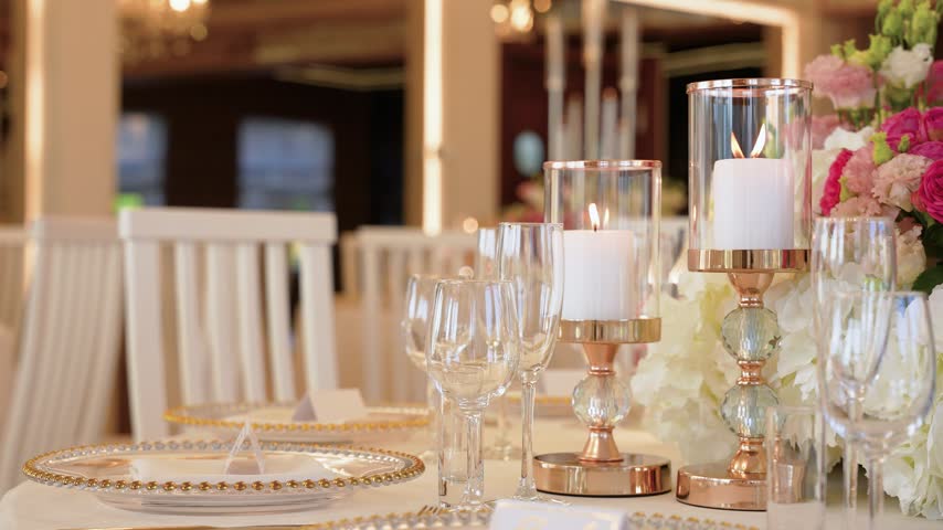 Luxurious banquet hall table features gold-rimmed plates, crystal glasses, and rose-gold candle holders. Soft, ambient lighting highlights floral centerpieces in a refined, festive atmosphere.