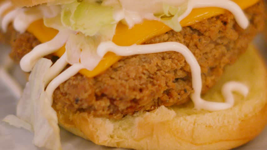 Close-up of Southern Fried Chicken Burger with Cheese, Lettuce and Mayonnaise. Tasty Junk Food.