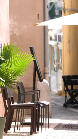 Static shot of vacant restaurant tables and chairs on a sunny street in Cassis.
