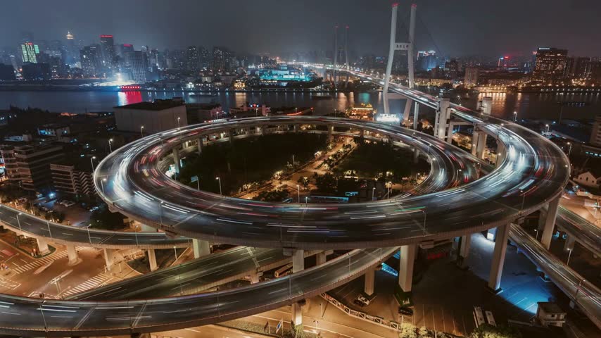 Aerial view captures iconic Shanghai Nanpu Bridge spiral highway interchange at night.