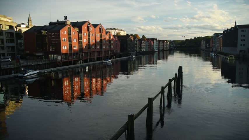 Red timber wharf houses reflected in the calm Nidelva, Trondheim, Trondelag, Norway
