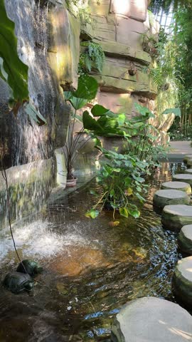 Small decorative waterfall with plants in greenhouse of Berlin Botanical garden in Germany