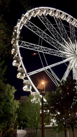 Close-up view of an illuminated Ferris wheel against the dark night sky in Budapest, Hungary, creating an atmospheric urban tourism scene