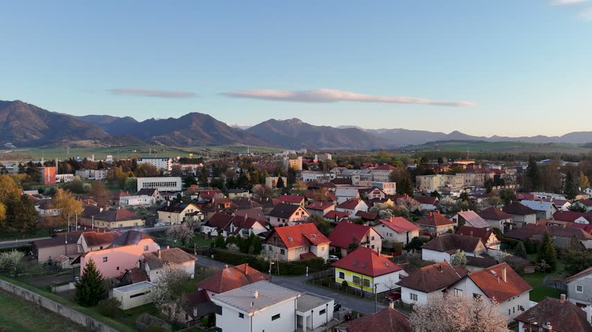 Aerial drone footage of Vah river bridge through liptovsky mikulas town at sunset with Low Tatras mountains, Slovakia