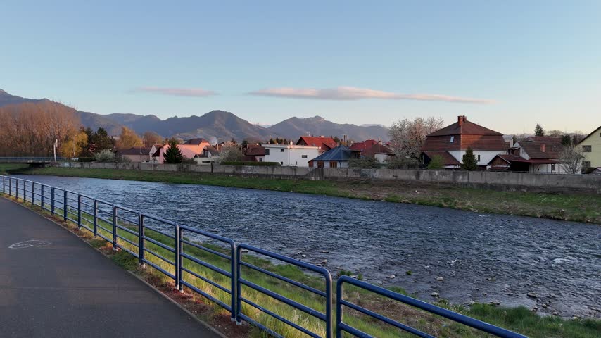 Aerial drone footage of Vah river bridge through Liptovsky Mikulas town at sunset with Low Tatras mountains, Slovakia