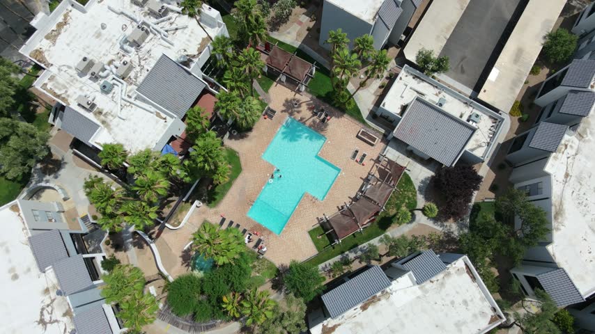 Drone aerial view of a Las Vegas resort featuring a sparkling blue swimming pool, palm trees and comfortable sun loungers, showcasing a luxurious vacation atmosphere, relaxation and resort lifestyle